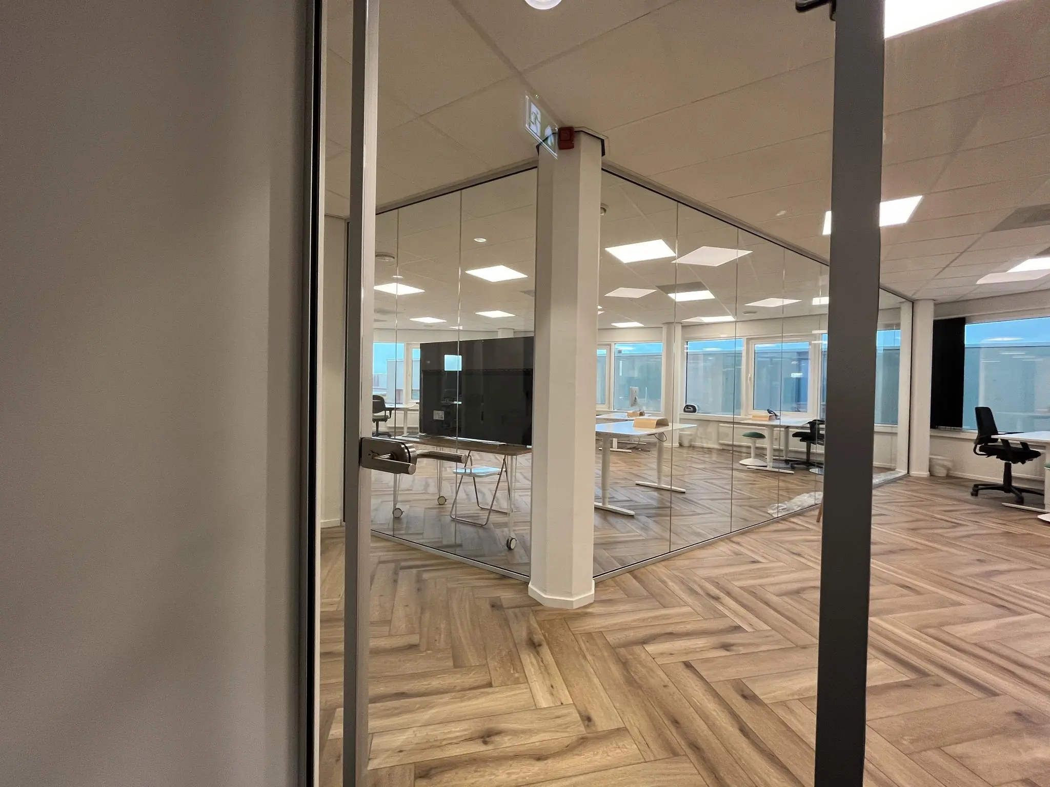 Moderne kantoorruimte aan de Lange Dreef met glazen vergaderruimte en houten visgraatvloer.